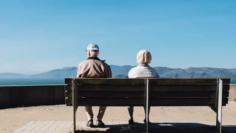 Un couple de personnes âgées assis sur un banc face à la mer